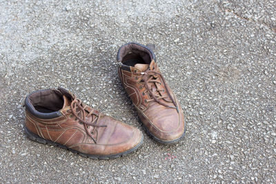 Old brown leather shoes on cement floor. pair of old dirty brown leather shoes.