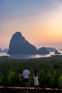 Rear view of men on mountain against sky during sunset