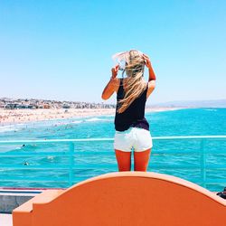 Rear view of woman standing in front of sea