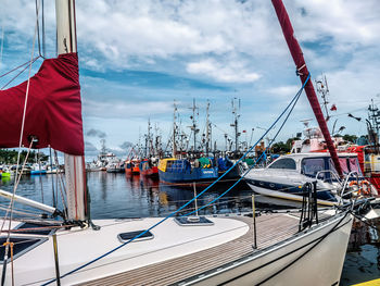 Boats moored at harbor against sky