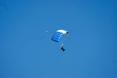 Low angle view of paragliding against clear blue sky