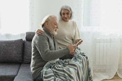 Senior couple sitting on couch with digital tablet