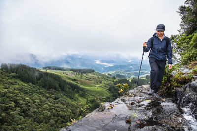 Woman exploring small waterfall in the mist of sri lankan highlands