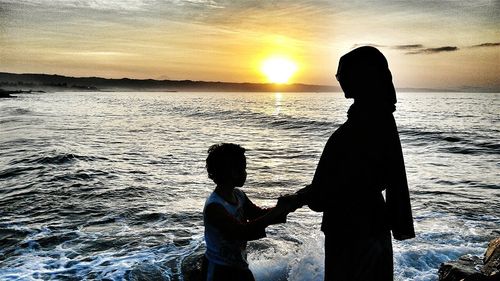 Silhouette of people on beach at sunset