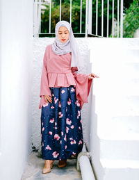 Portrait of young woman standing against white wall