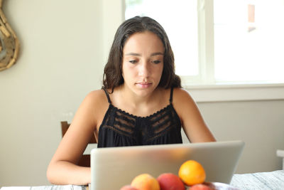 Portrait of young woman using phone at home