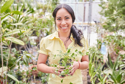 Portrait of a smiling young woman holding plant