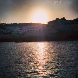 Sunset over river with buildings in background