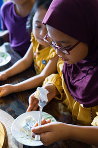 High angle view of girls eating cake on table at home