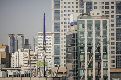 Crane by buildings in city