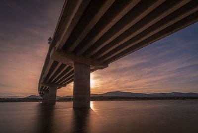 Bridge over river against sky during sunset