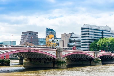 Blackfriars bridge over thames river against cloudy sky in city