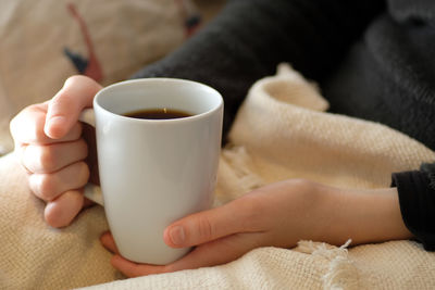 Close-up of hand holding coffee cup