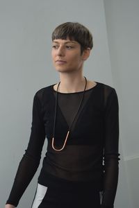 Young woman looking away while standing against wall