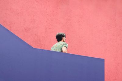 Young woman standing against red wall