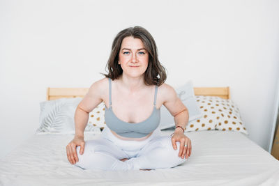 Portrait of woman sitting on bed at home