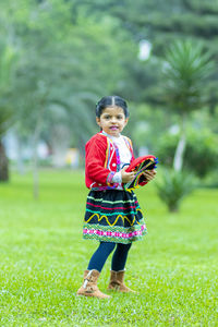 Portrait of smiling girl in traditional clothing while standing on grass