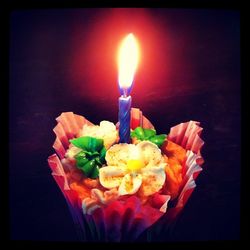 Close-up of burning candle over black background