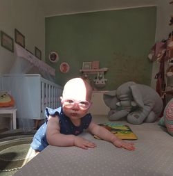 Portrait of boy sitting on bed at home