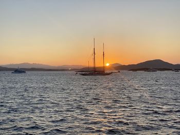 Sailboats sailing in sea against sky during sunset