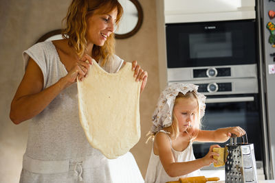 Little girl with mam cooking pizza in the kitchen