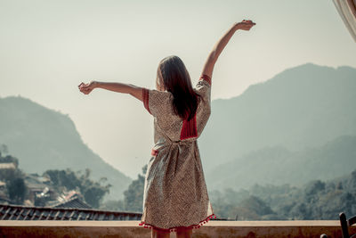 Rear view of woman looking at mountain range against sky