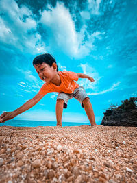 Full length of young man at beach against blue sky