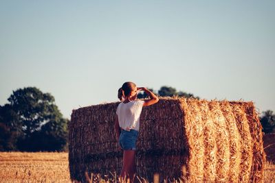 Rear view of man photographing on field against clear sky