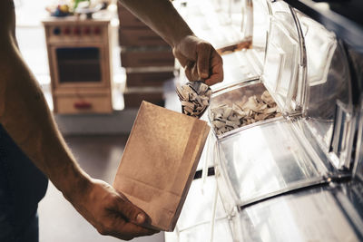 Male customer filling slice coconut in paper bag at organic shop