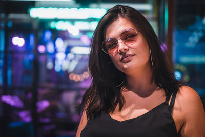 Portrait of beautiful woman wearing sunglasses at night