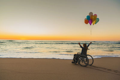 Woman sitting on wheelchair at beach