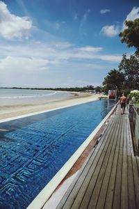 Swimming pool by sea against sky