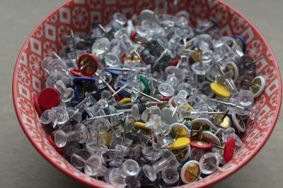 Variety of thumbtacks in container on table