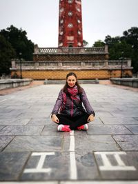 Portrait of smiling woman sitting on steps against building