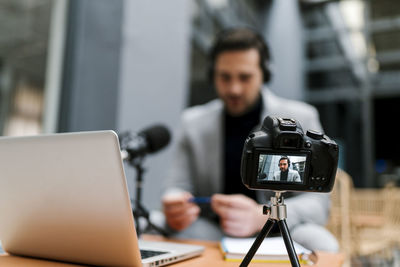 Businessman filming vlog through camera while sitting at cafe