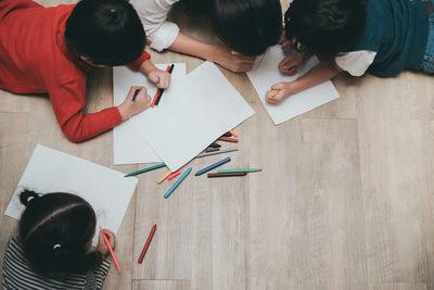 High angle view of mother and children drawing on papers