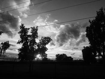 Low angle view of power lines against cloudy sky