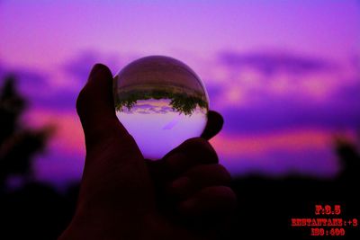 Close-up of human hand against sky during sunset