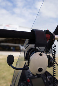 Close-up of camera hanging on cable against sky