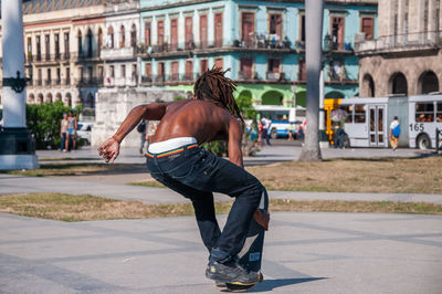 Rear view of man skateboarding on street in city