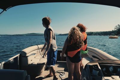 Rear view of women standing on sea against sky