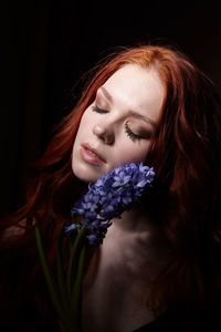 Portrait of a girl with long red hair, good skin, with long eyelashes, closed eyes, flower hyacinth