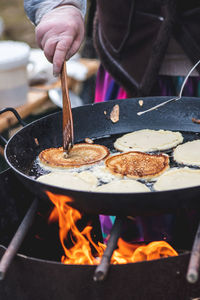 Cooking blini, blin or blynai, pancakes traditional sweet food, preparing outdoor on an open fire