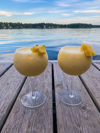 Close-up of lemon on table by lake against sky