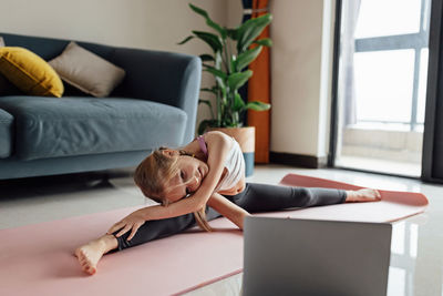 Low section of woman sitting on sofa at home