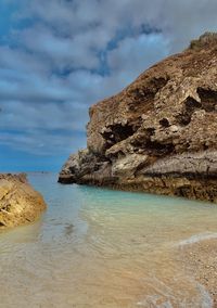 Rock formation on beach against sky