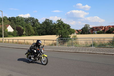 Man riding motorcycle on road against sky