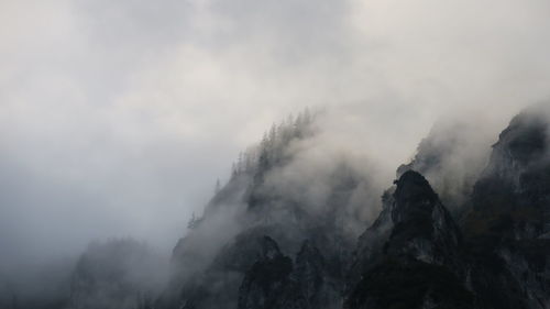 Low angle view of fog in mountains against sky