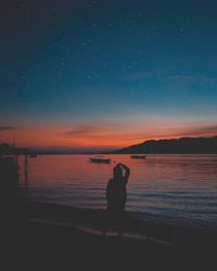 Silhouette man standing on beach against sky during sunset