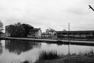 Bridge over river by buildings against sky